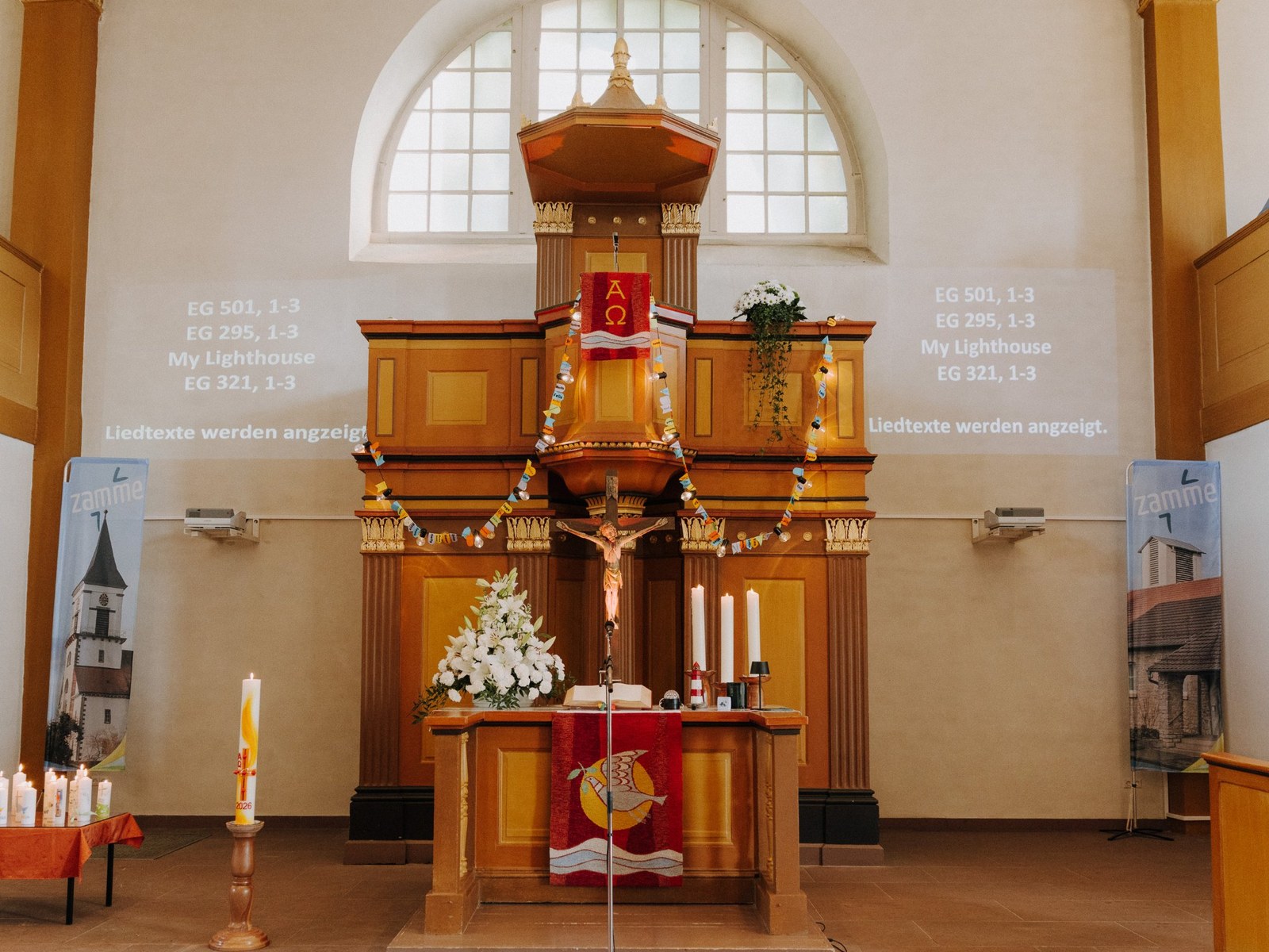Altarraum der Weinbrennerkirche in Wössingen zur Konfirmation mit Kanzel, Kruzifix, Blumenschmuck und Konfirmationskerzen