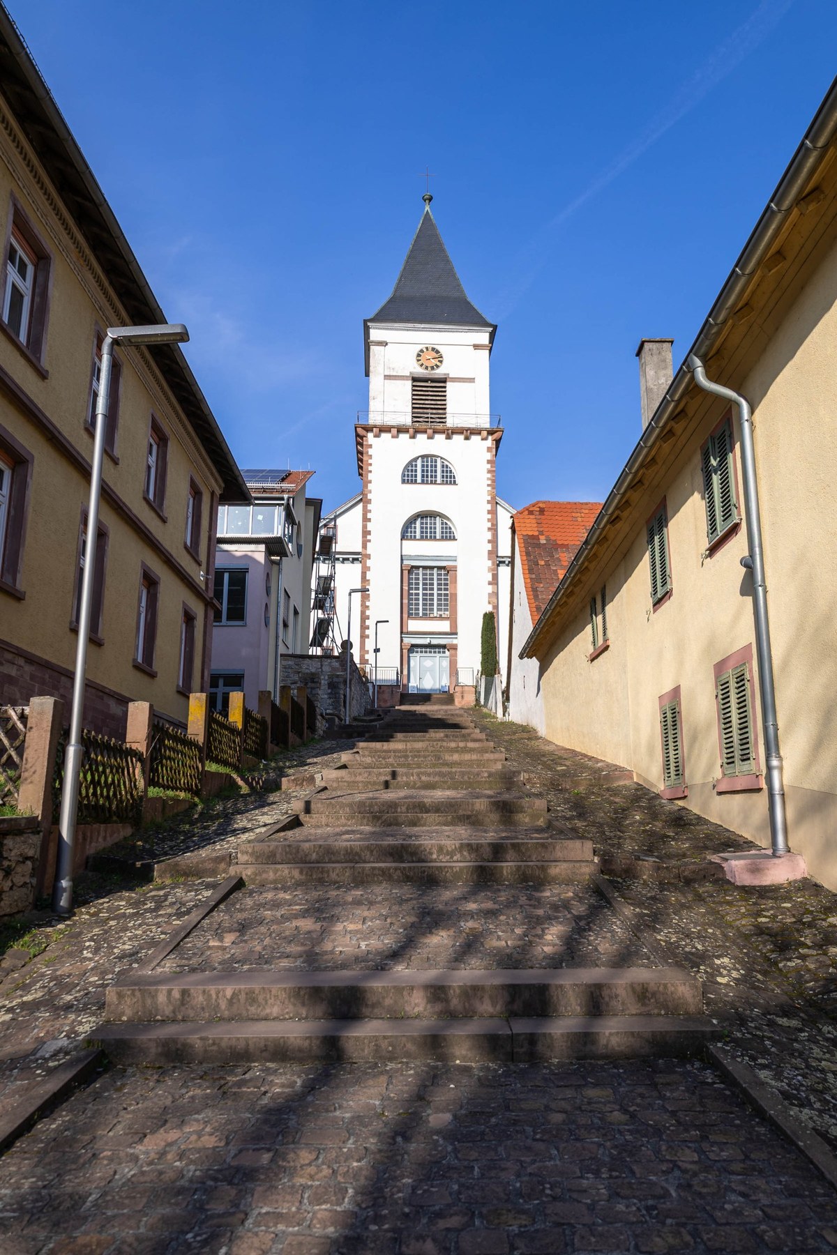 Weinbrennerkirche in Wössingen: der Kirchturm am Ende der Kirchentreppe, von der Straße aus gesehen